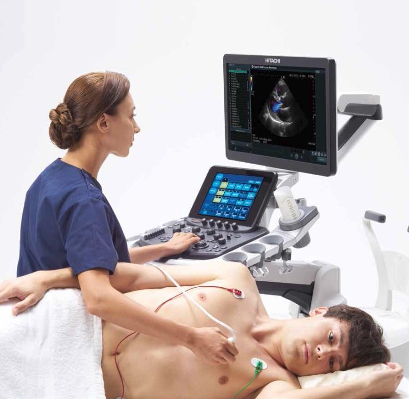 Bệnh nhân nằm trên giường chuẩn bị siêu âm tim bác sĩ đang bôi gel lên ngực